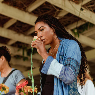 Black woman with braids smelling a rose