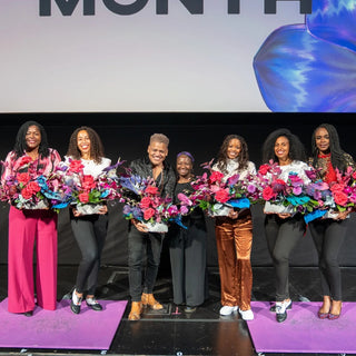 Group of POC women on stage holding flower bouquets.